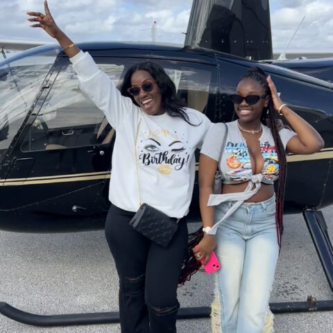 Happy customers posing in front of Magic Air Tours helicopter after a private Miami tour