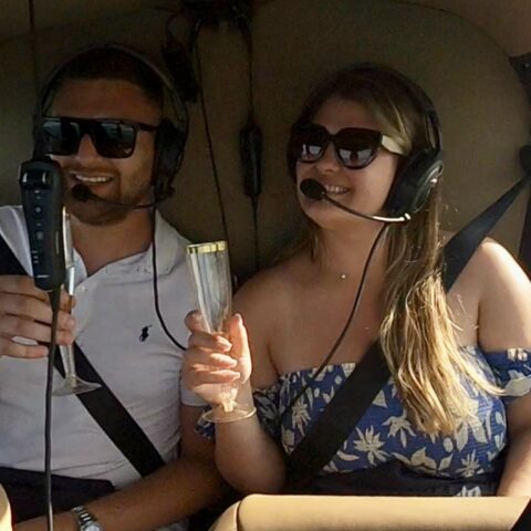 Couple enjoying champagne on a romantic helicopter ride over Miami's South Beach and downtown skyline.