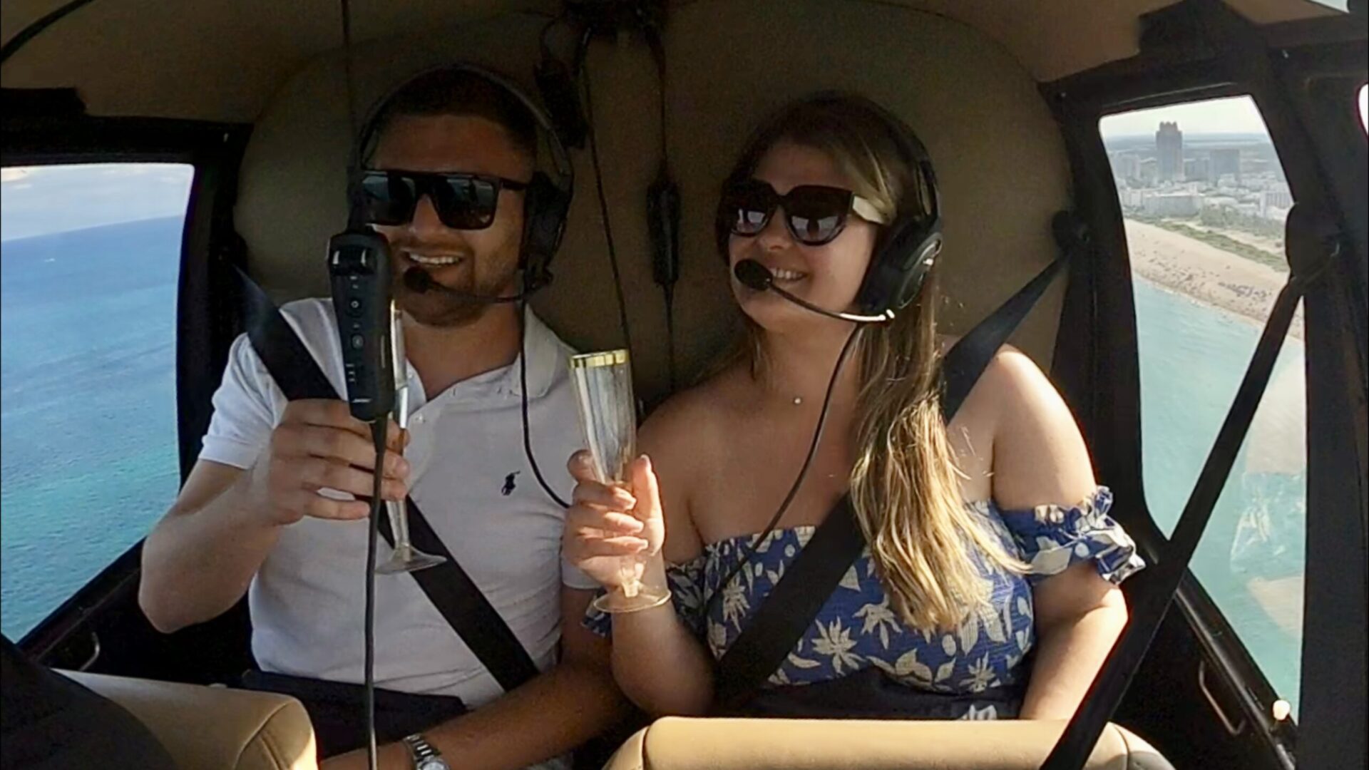 Couple enjoying champagne on a romantic helicopter ride over Miami's South Beach and downtown skyline.