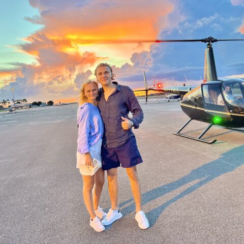 Couple about to board a sunset helicopter tour over Miami with Magic Air Tours, vibrant sunset in the background